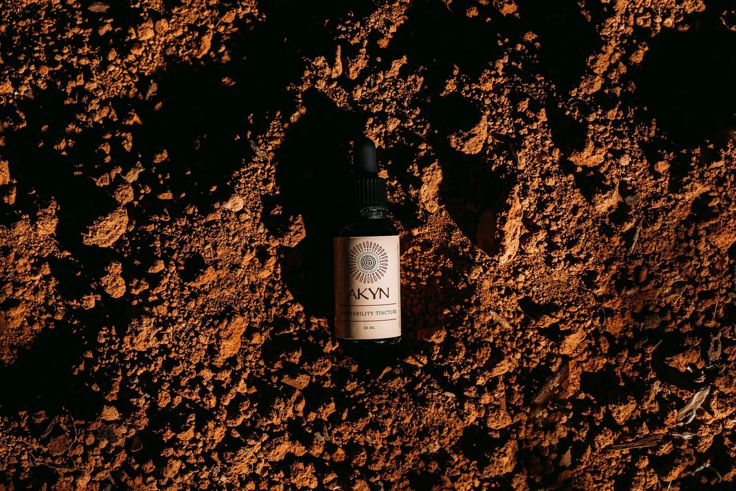 The bottle against a warm rust-coloured textured setting.