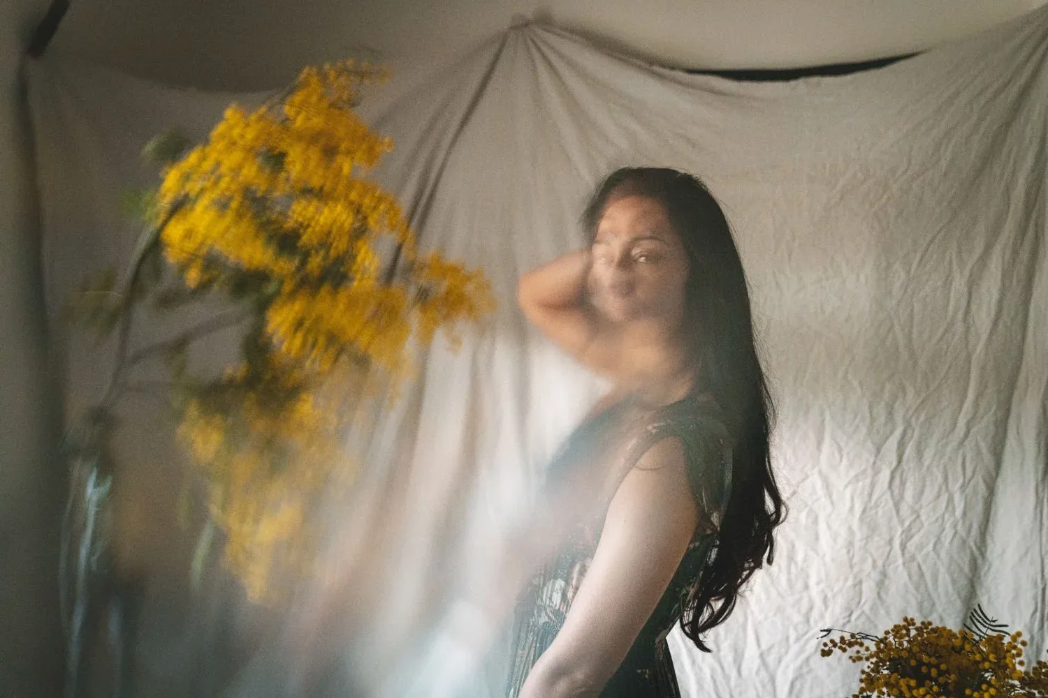 Sunshine Connelly photographed beside yellow blossom and pale fabric.